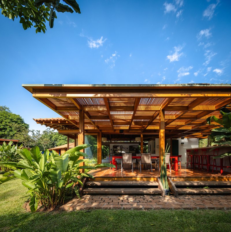 Open-air living space with slatted timber ceiling and teak deck looking toward interior dining area