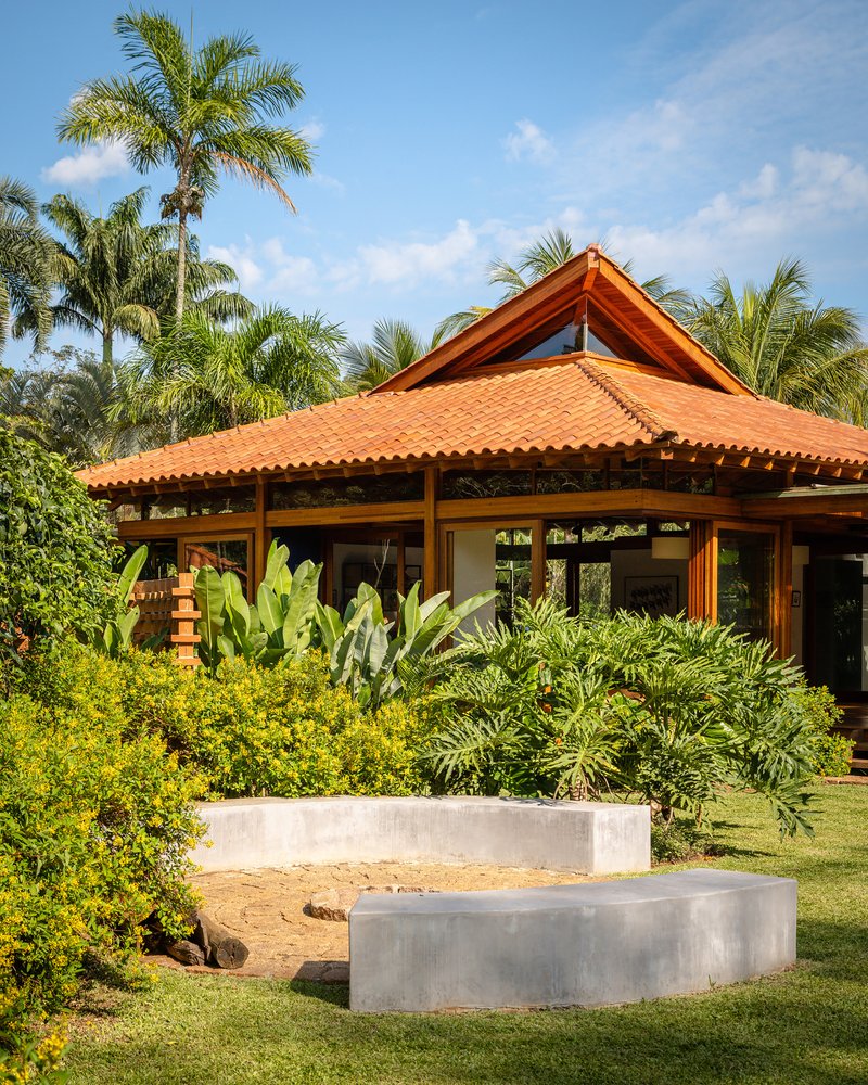 Clay tile roof with raised timber gable above planted lawn with paired concrete seating elements
