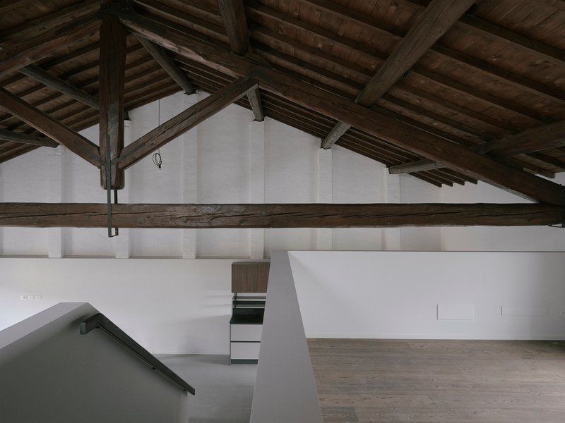 Upper level gallery with white walls and exposed timber beams and columns overhead