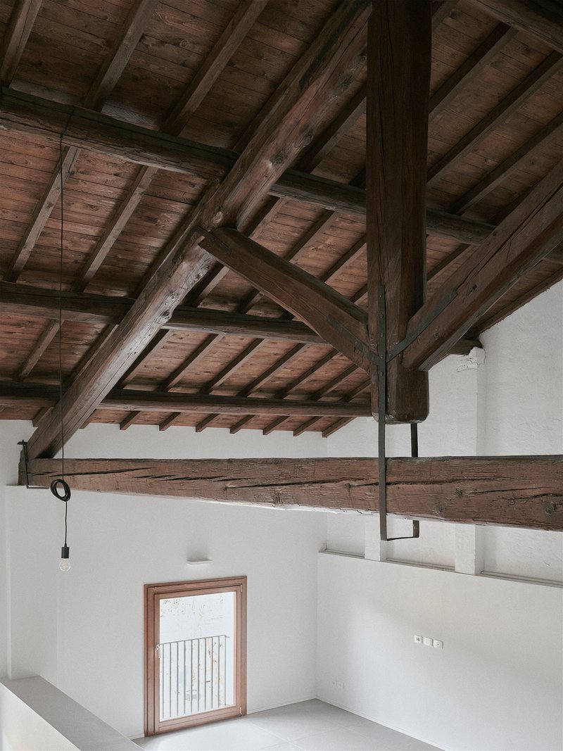 Mezzanine level with exposed timber roof structure and metal railing overlooking a lower room