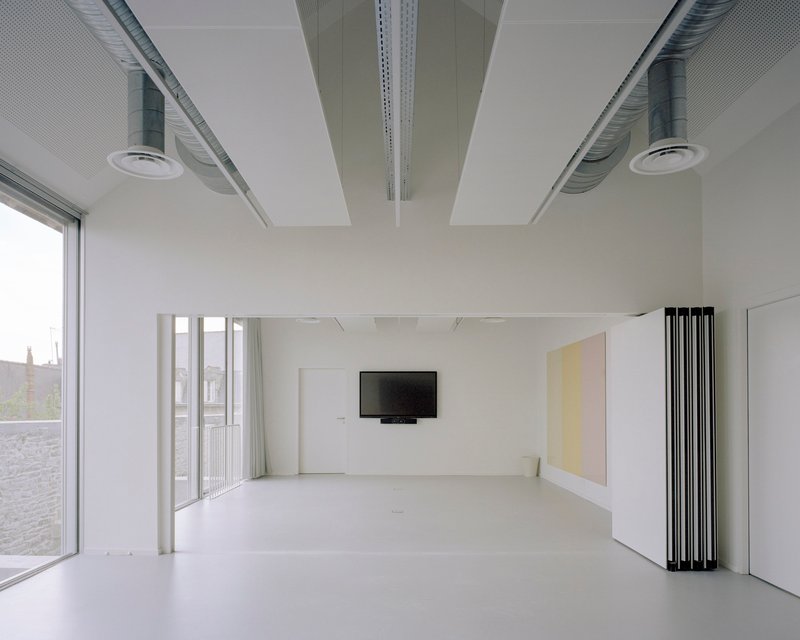 Interior space with retractable partition panels revealing a wall-mounted screen and folding furniture elements