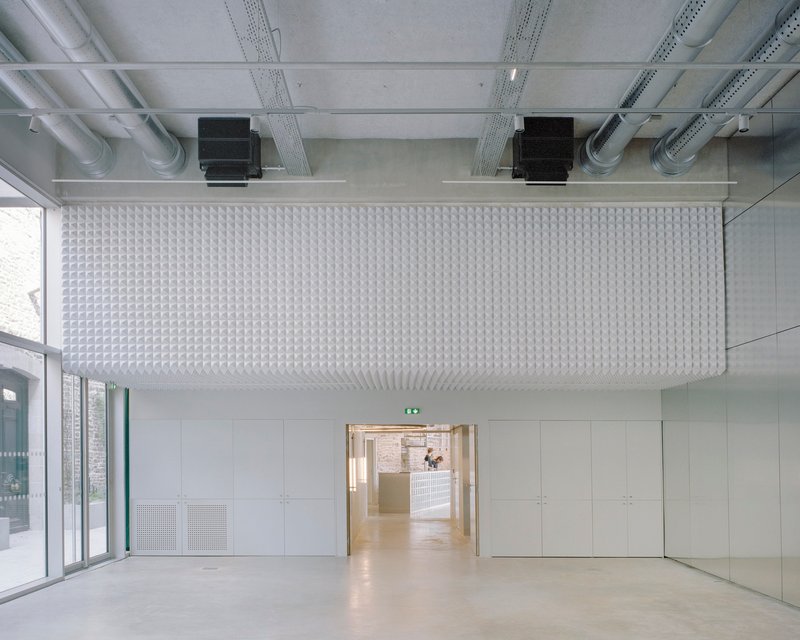 Interior room with textured acoustic ceiling panel, exposed mechanical systems and polished concrete floor