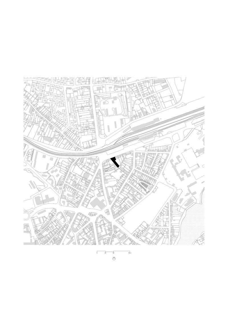 Site plan drawing showing building footprint highlighted in black within dense urban fabric and adjacent railway lines