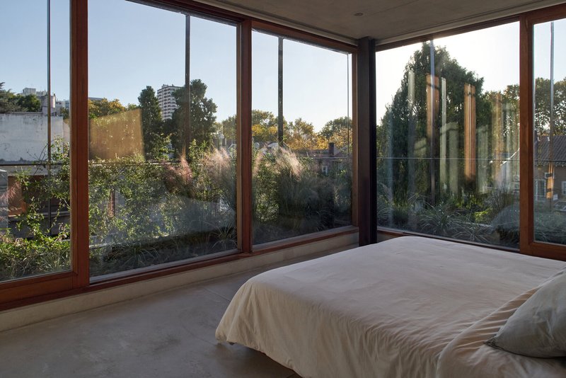 Corner glazing with timber frames opening onto a planted terrace at dusk