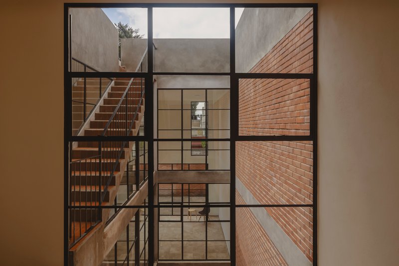 Black steel window framing views into the interior courtyard and timber staircase beyond
