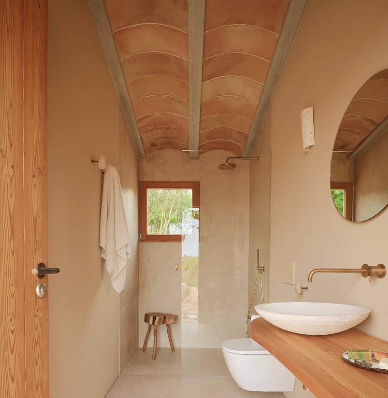 Bathroom with vaulted timber ceiling and arched opening leading to a walk-in shower with garden view
