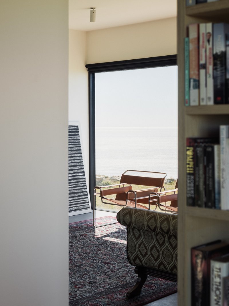 Doorway opening to terrace with lounge chair and louvered screen framing distant landscape