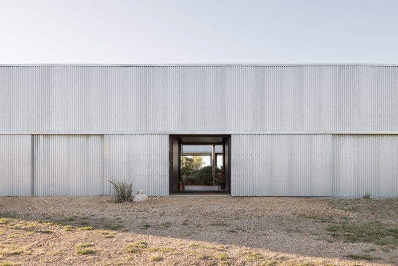 Central entry portal framing a view through the building to vegetation beyond