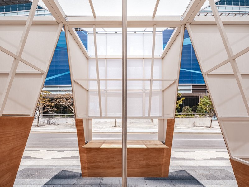 Interior view through the timber frame structure showing twin benches and triangular apertures to the street