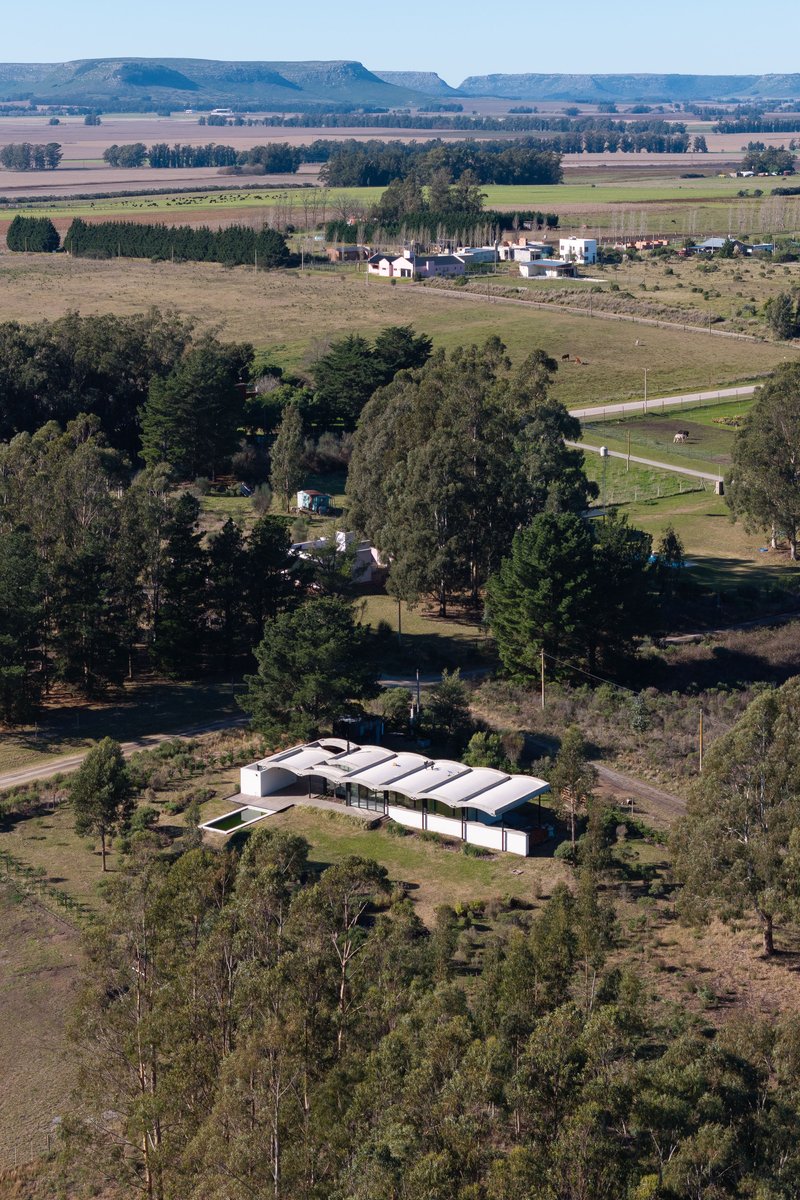 Aerial view of the barrel vaulted roof structure surrounded by scattered trees and farmland