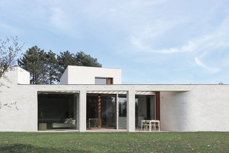 Garden facade with white brick walls and full-height glazed openings onto a lawn