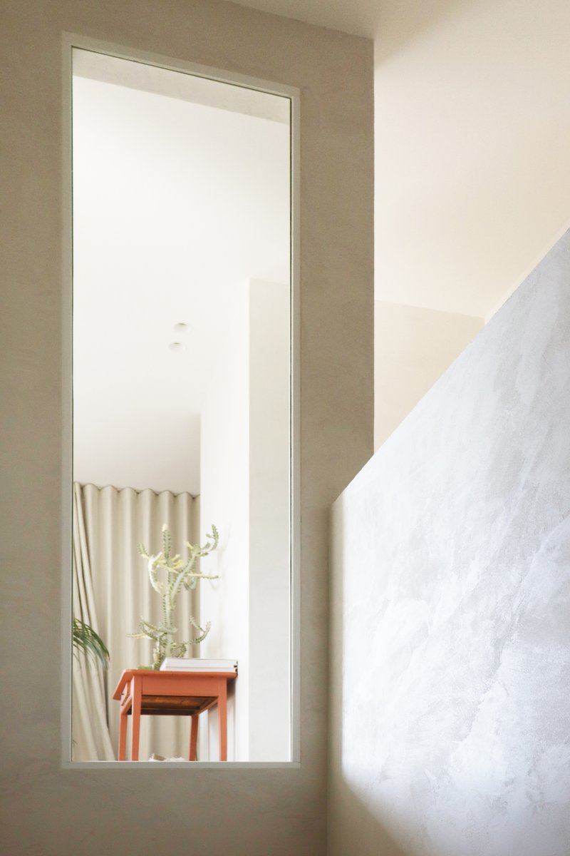 Tall narrow window framing a view of a console table with cactus and wall hangings beyond