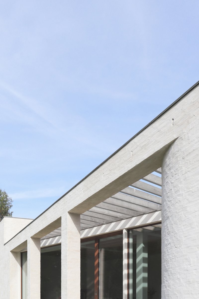 Painted brick facade with concrete slatted canopy under a clear sky