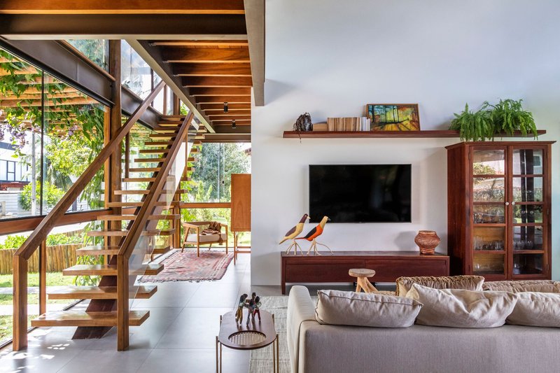 Living room with timber open-tread stair and exposed ceiling beams framing views to the terrace