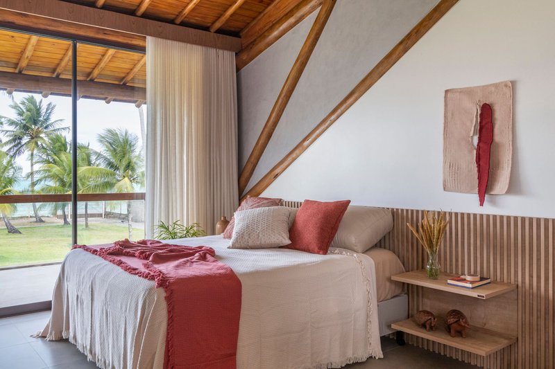Bedroom with glazed doors opening to palm trees and fluted timber headboard beneath exposed rafters