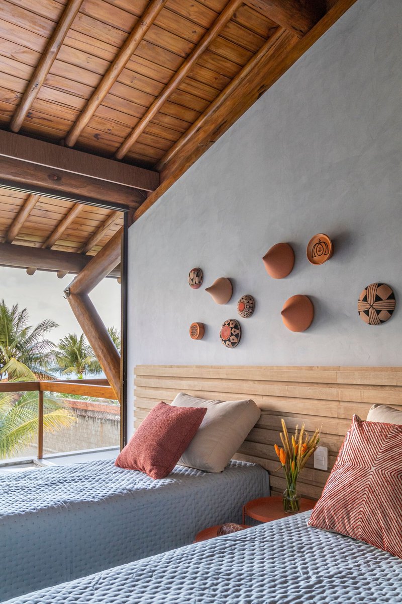 Bedroom wall with terracotta disc artworks above horizontal timber slat headboard and opening to palms