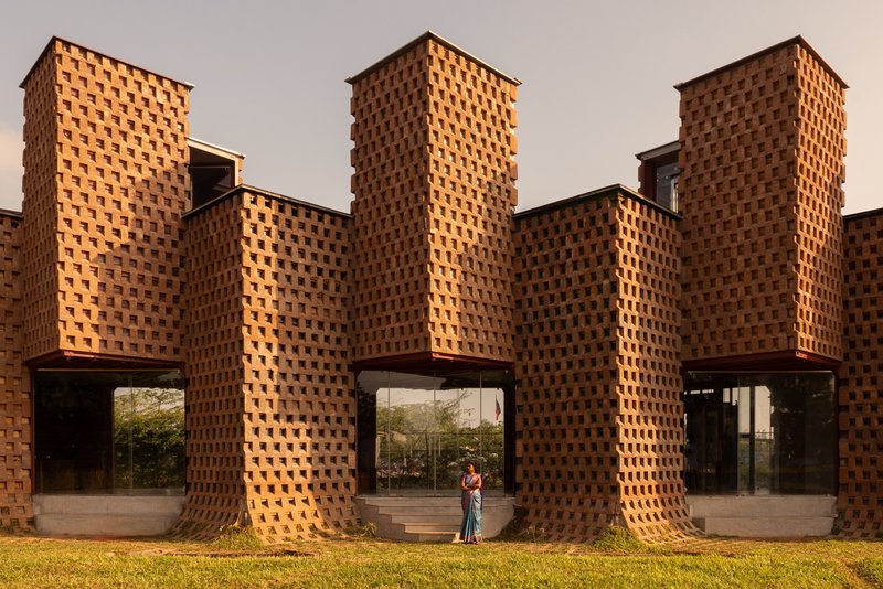 Rhythmic brick piers with staggered openings forming arched passageways at ground level at dusk