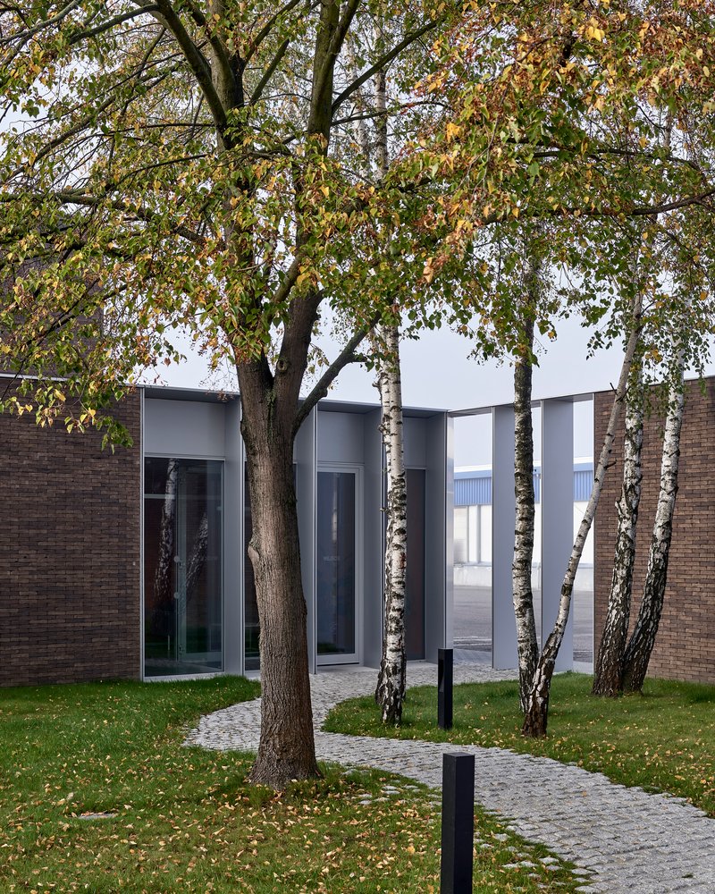 James and Mau Wrap a Polish Industrial Office in Dark Brick and a Birch Forest