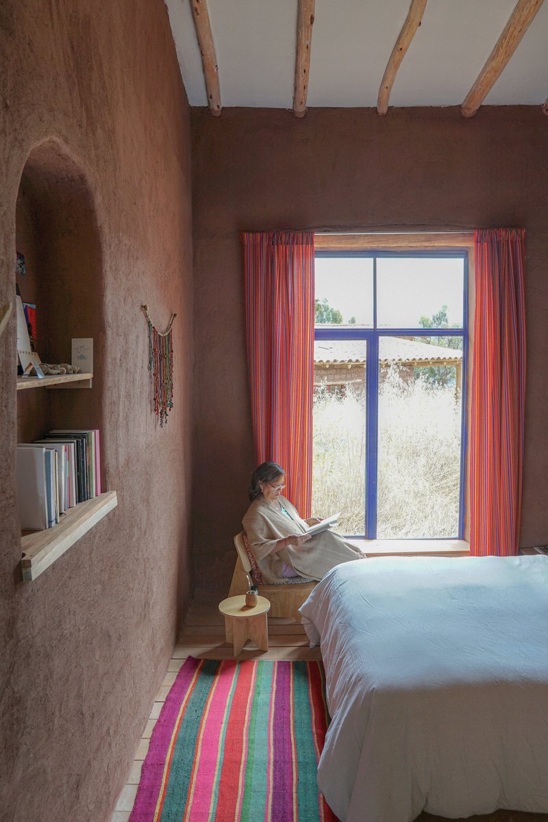 Bedroom nook with person reading by a window framed with striped textile curtains