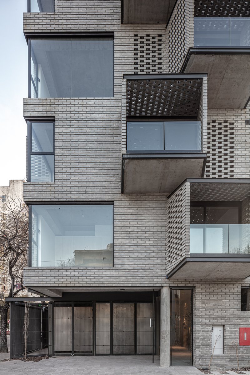 Close-up of the layered brick facade showing alternating perforated screens and glazed openings in daylight