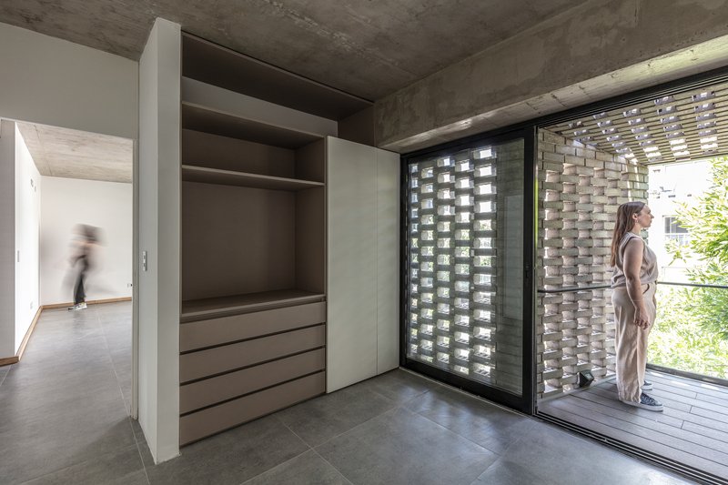 Bedroom with built-in wardrobe opening to a terrace through sliding glass doors and brick screen wall