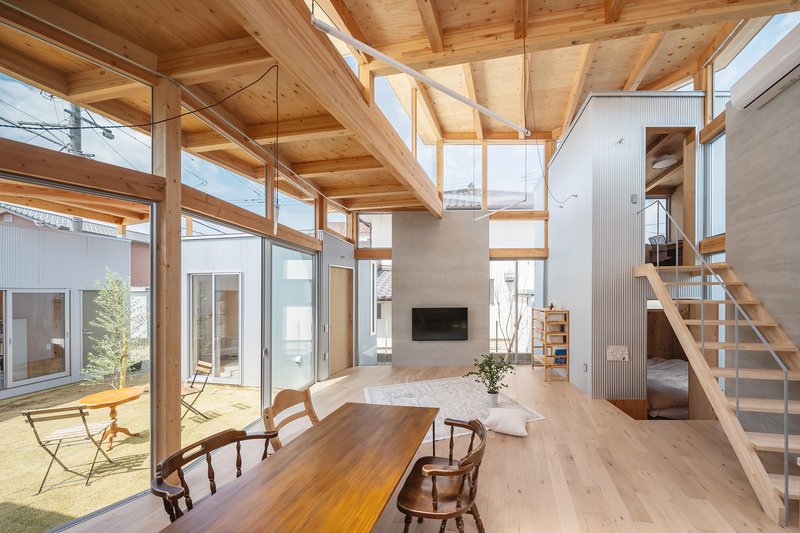 Double-height living space with exposed timber beams and glazed walls overlooking an interior courtyard
