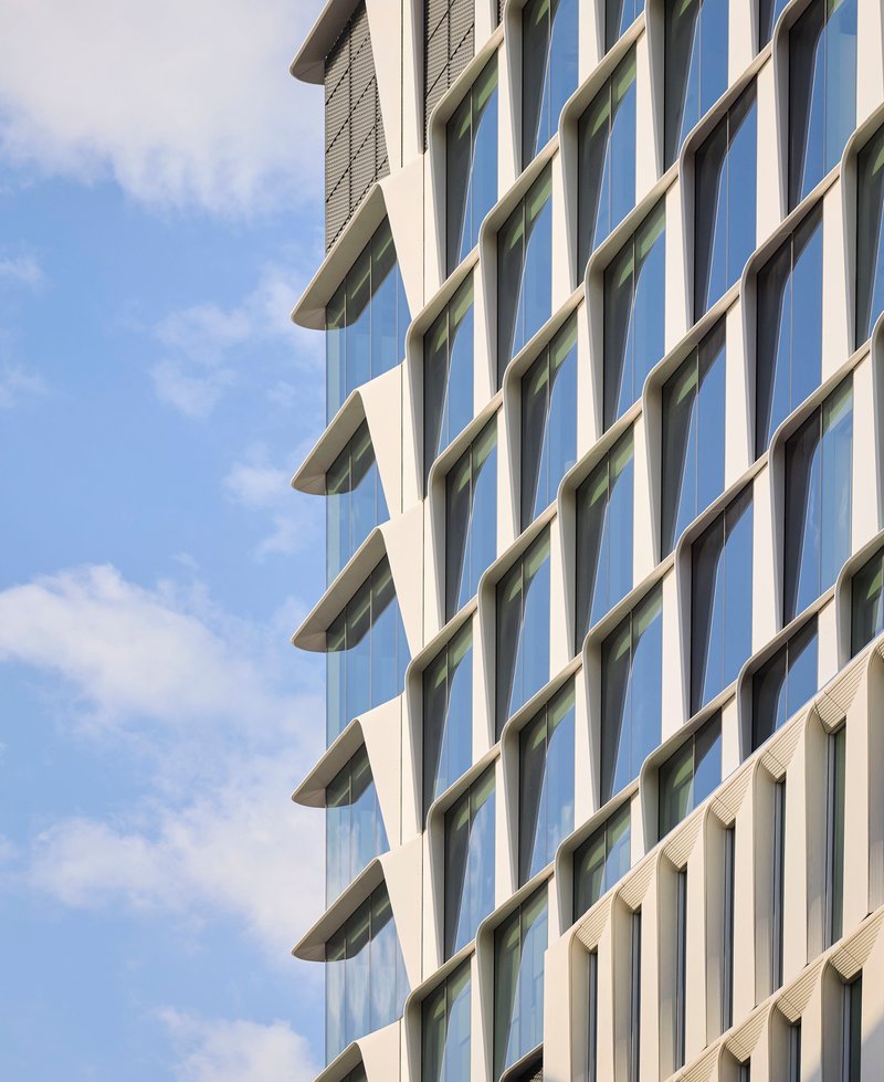 Oblique view of the alternating glass and concrete facade against scattered clouds