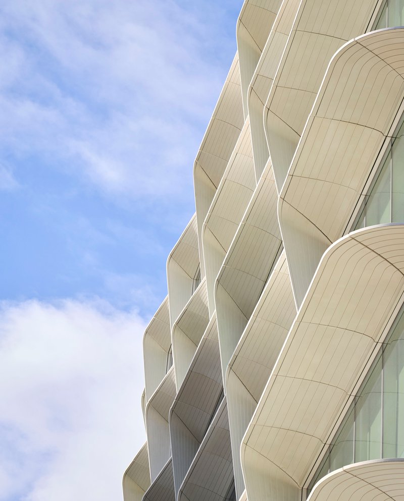 Close-up of the curved balcony soffits and ribbed panel cladding in daylight