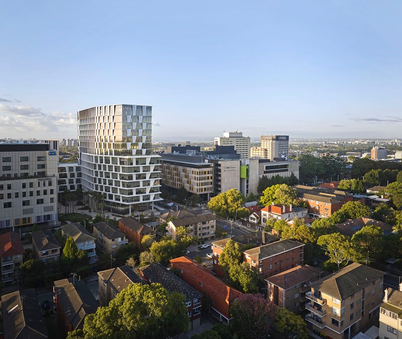 The stepped facade with offset balconies viewed from above at dusk over suburban rooftops