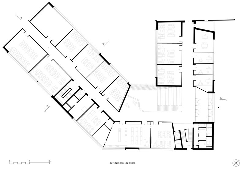 First floor plan drawing showing angled classroom wings with a central stairwell and terrace