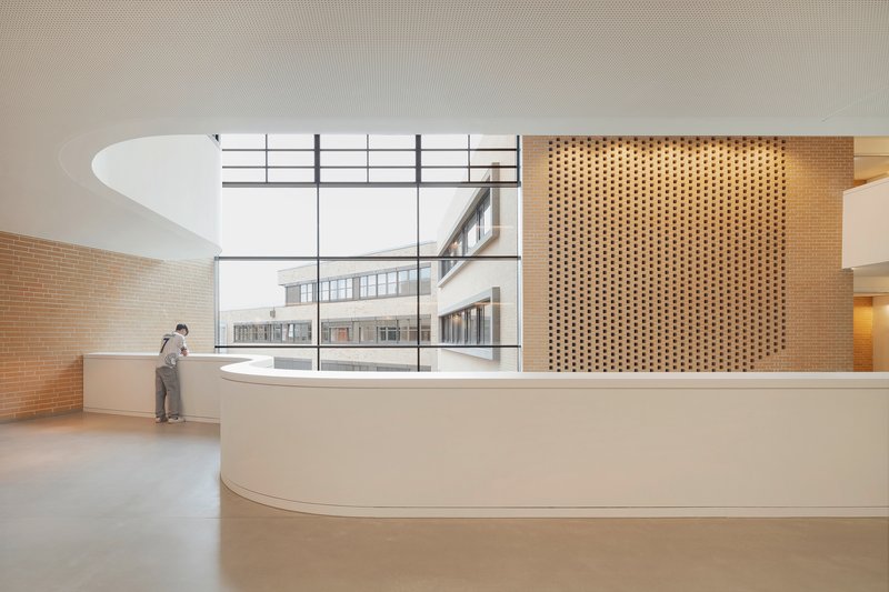 Curved reception counter with perforated wood screen and clerestory window overlooking an adjacent building