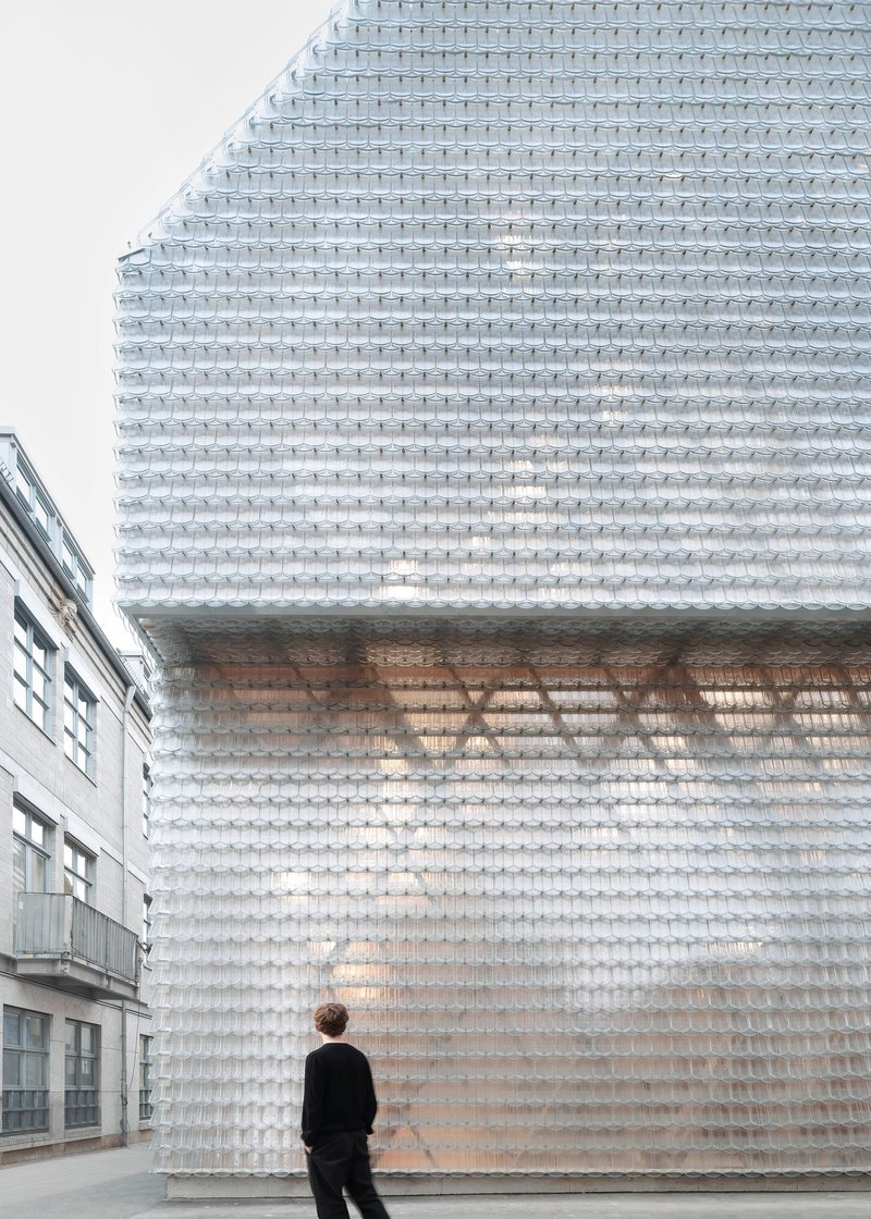 Translucent glass brick facade with recessed opening and a person standing at street level