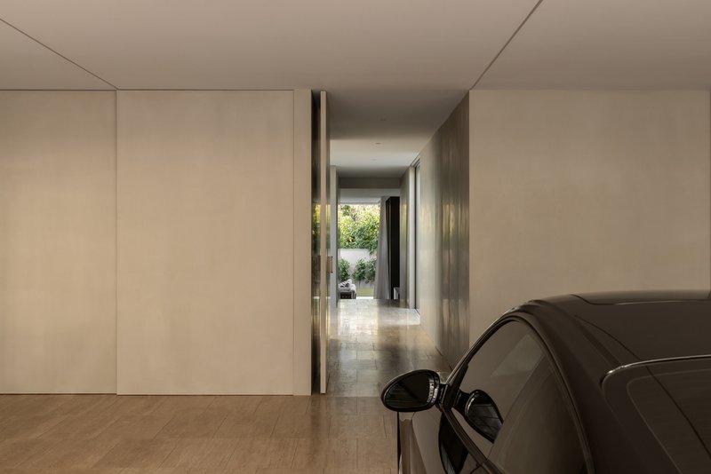 Pale timber-floored garage with flush wall panels and a view through to a sunlit courtyard