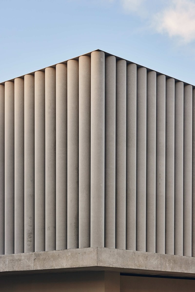 Close-up of vertical concrete fins wrapping the corner of the cantilevered upper level
