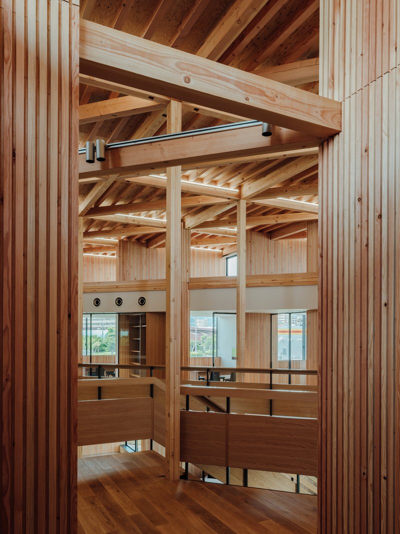 View through timber columns showing layered mezzanine platforms with vertical slatted screens beneath exposed joists