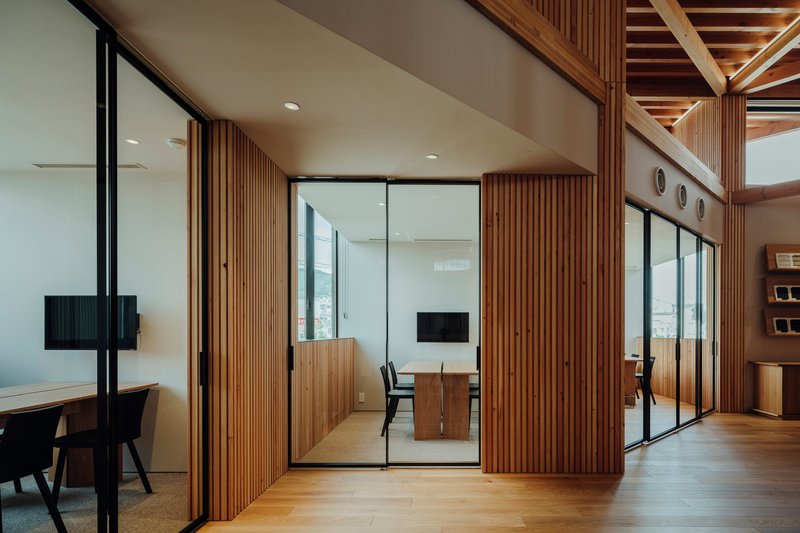Glass-walled meeting rooms with vertical timber slat screens and black-framed doors