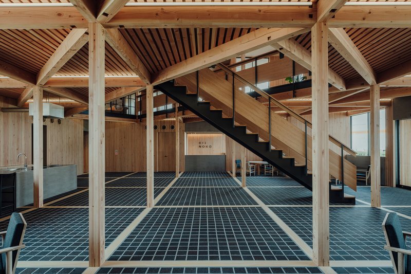 Open interior showing exposed timber frame with blue grid floor tiles and steel staircase to mezzanine