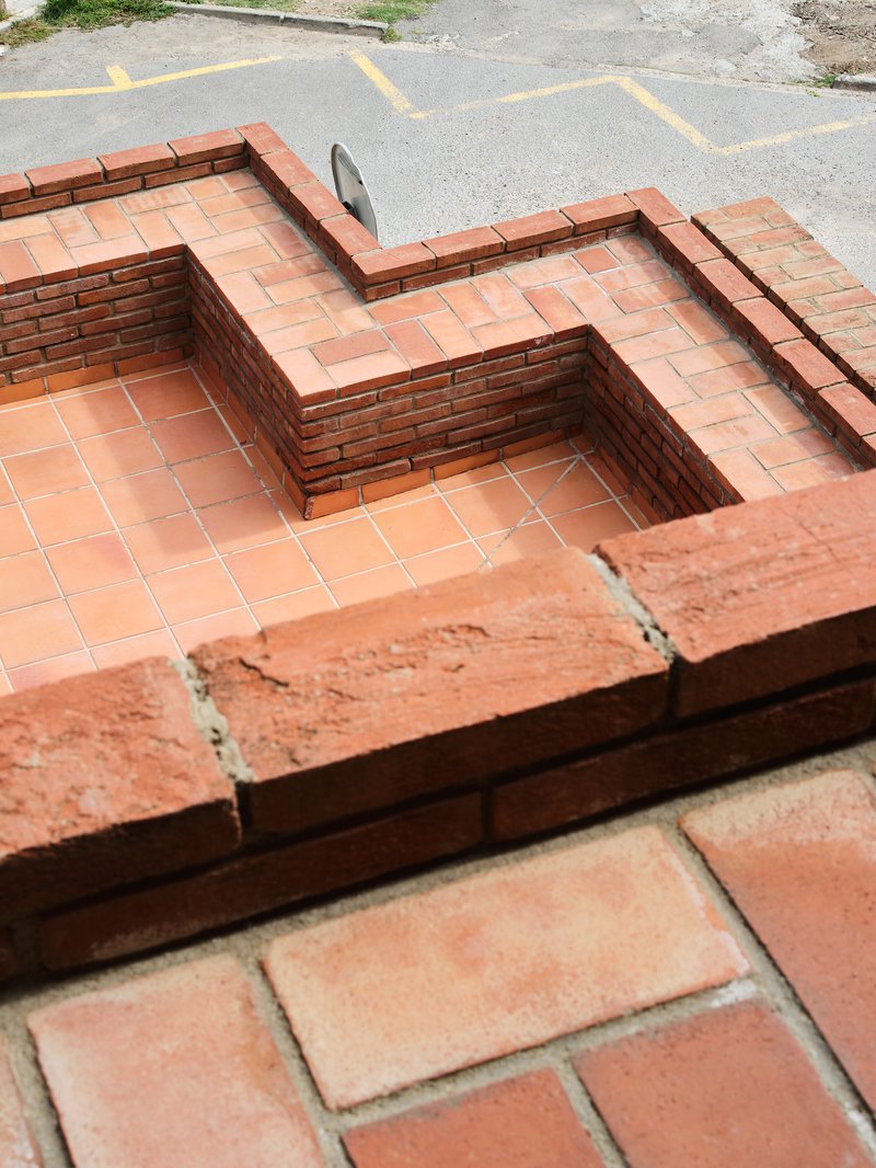 Close-up of stepped brick and terracotta tile detail at roof level with street pavement visible