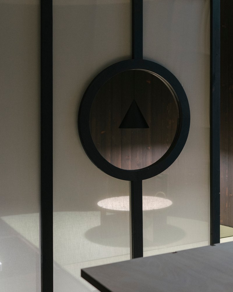 Circular mirror mounted on vertical steel bar casting shadow over concrete counter below