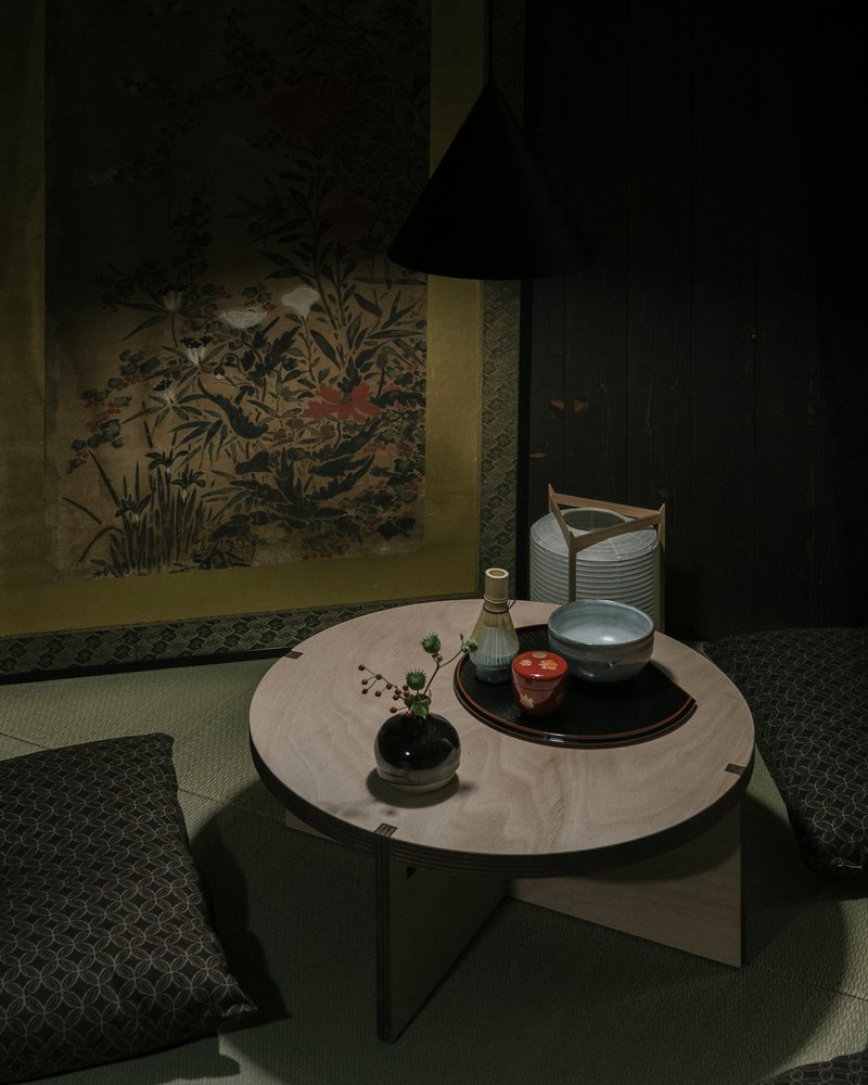 Low stone table with tea service against a painted scroll depicting flora and fauna
