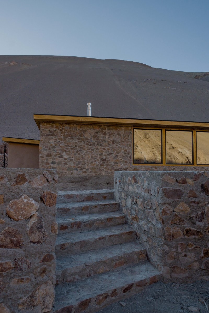 Stone staircase ascending to the flat-roofed structure with ribbon windows at twilight