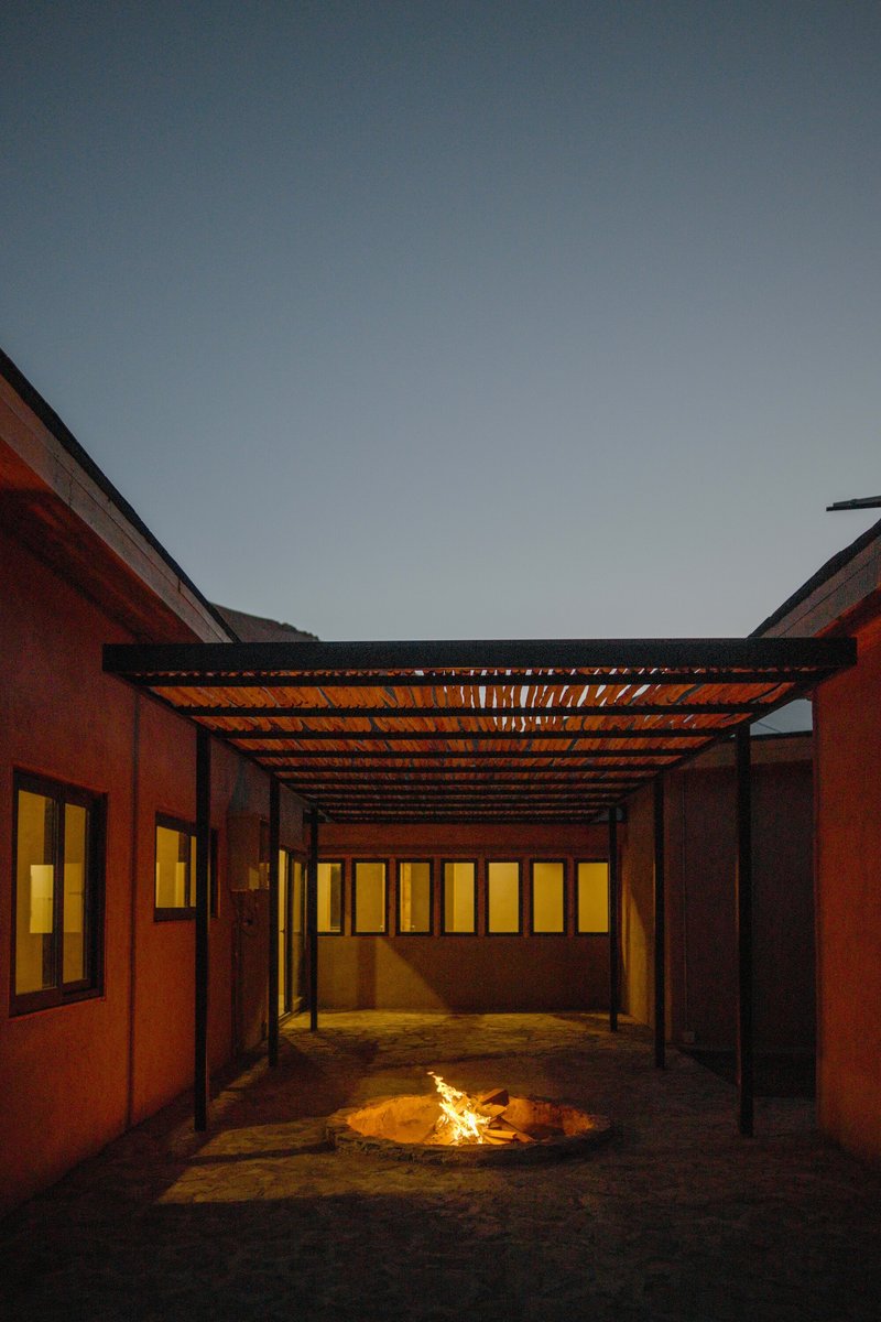 Covered courtyard with fire pit centered under timber slat canopy at twilight