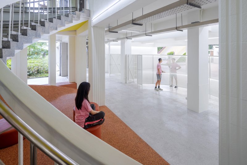 View from orange rubber staircase landing toward white columns and movable partitions below