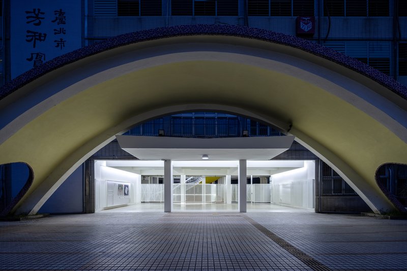 Arched entrance with glowing white interior set beneath a curved vault at twilight