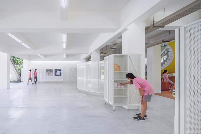 White modular storage units on wheels with perforated metal panels in a column-filled interior