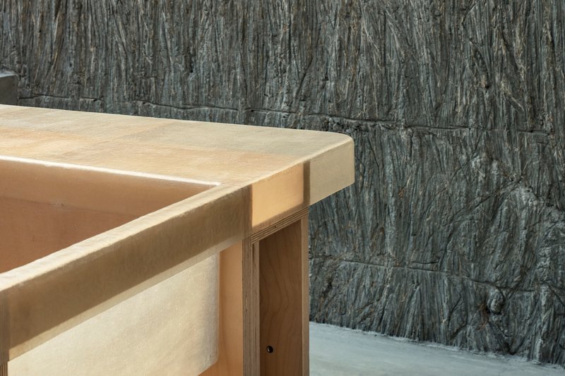 Detail of plywood countertop edge against rough-textured vertical concrete block wall
