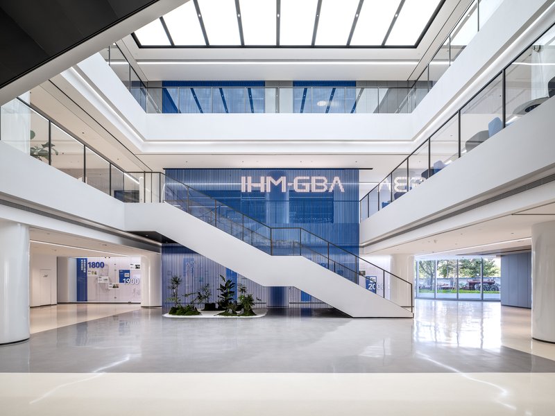Multilevel atrium with diagonal white staircase and skylight above polished stone floor