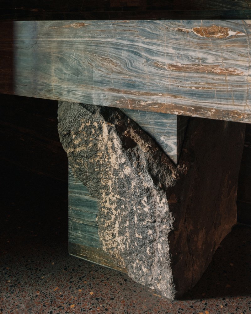 Close-up of marbled stone bench with rough quarried block base on terrazzo flooring