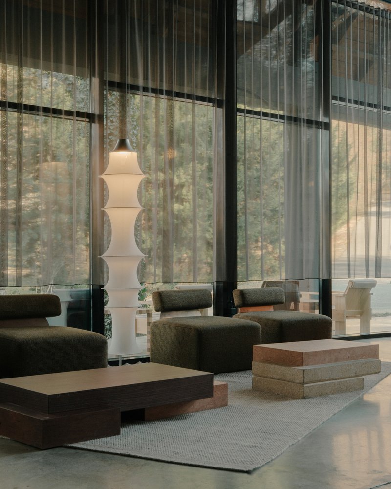 Double-height lobby with suspended white lantern and marbled glass wall beyond sheer curtains