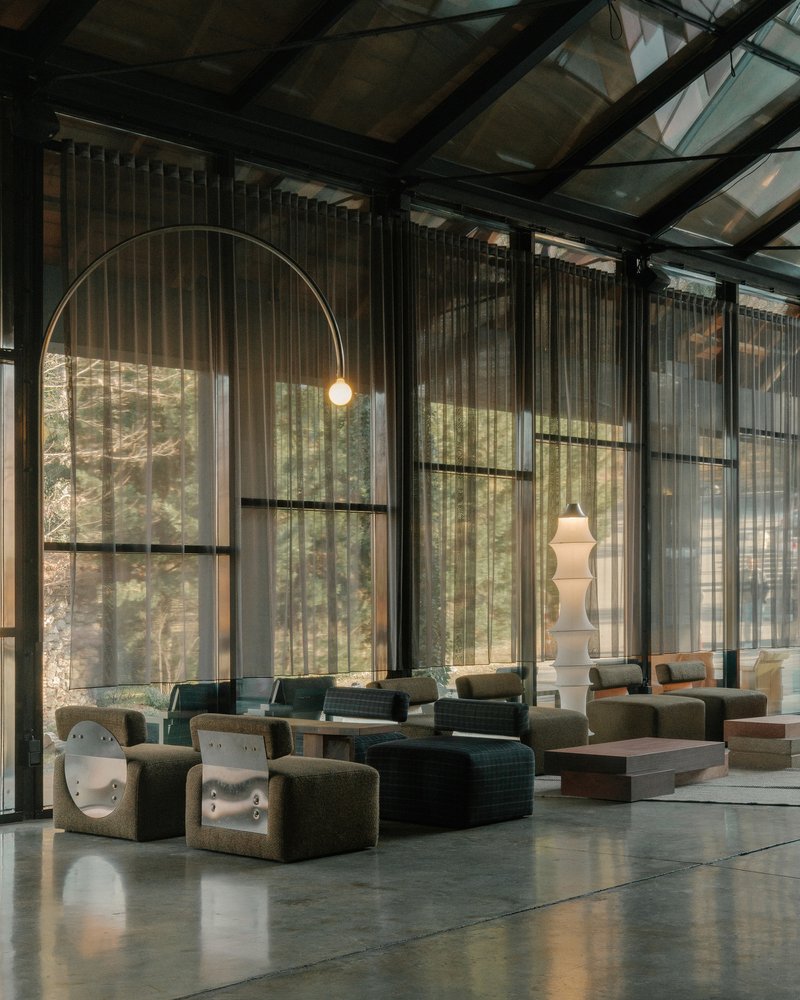 Seating area beneath an arched pendant light with filtered daylight through sheer curtains